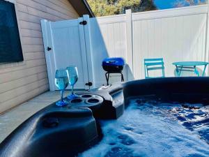 uma banheira de hidromassagem com 2 copos, uma mesa e cadeiras em Butterfly Suite Hot Tub BBQ Private em Ahwahnee