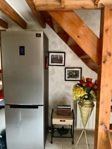 Il comprend une cuisine équipée d'un réfrigérateur et d'une table avec un vase de fleurs. dans l'établissement Gîte Maison Made in Normandie, à Bois-Normand-près-Lyre