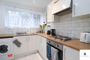 una cucina bianca con lavandino e lavastoviglie di Den Accommodation & Short Lets Greenwich London - 3 Bed House a Londra