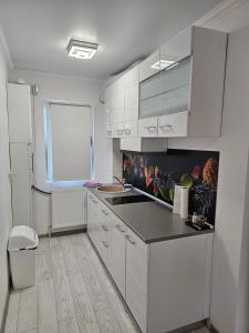 een keuken met witte kasten en een zwart aanrecht bij APARTAMENT 9 RO&MARIO Barlad in Bîrlad