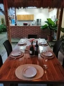 a wooden table with plates and wine glasses on it at Tagualodge Hostel Manglaralto in Manglaralto