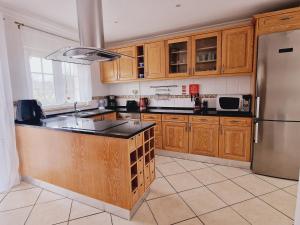 a kitchen with wooden cabinets and a stainless steel refrigerator at Villa Monte Branco in São Bartolomeu de Messines