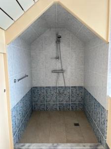 y baño con ducha y azulejos azules. en Huisje Marie Loosdrecht, en Loosdrecht