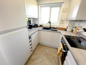 a kitchen with white cabinets and a sink and a window at Escape to Tranquil 1 bed, Poole in Canford Magna