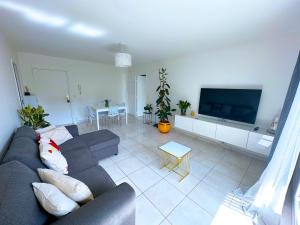 a living room with a couch and a flat screen tv at L'écrin du stade By UTA HOUSE in Saint-Denis