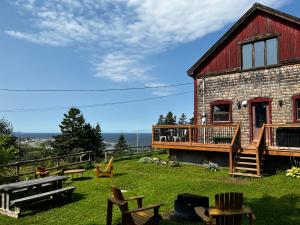 a brick house with a deck and a patio at Chalet Epicea in Sainte-Anne-des-Monts