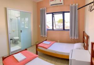 a bedroom with two beds and a bathroom with a shower at Poupahotel in Taubaté