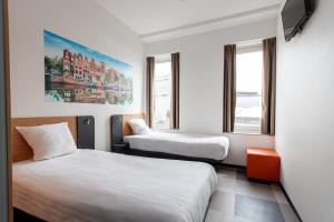 a hotel room with two beds and two windows at easyHotel Amsterdam Arena Boulevard in Amsterdam