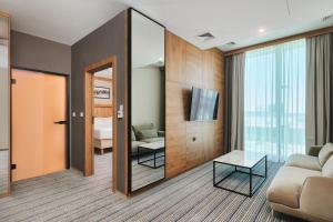 a living room with a couch and a mirror at Courtyard by Marriott Warsaw Airport in Warsaw