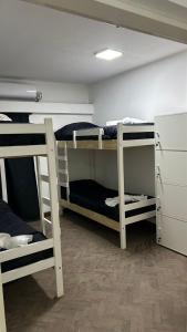 a room with three bunk beds and a refrigerator at NORTE HOSTEL in San Fernando del Valle de Catamarca