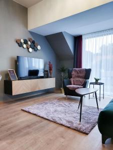 uma sala de estar com uma televisão, uma cadeira e uma mesa em Linden Apartman 107 - Adults Only em Mosonmagyaróvár