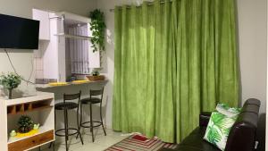 a living room with a green curtain and a kitchen at Thermas do Bandeirante in Caldas Novas