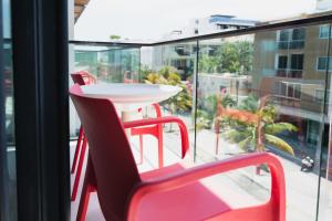 a red chair and a table on a balcony at Fiesta Inn Playa del Carmen in Playa del Carmen