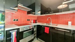 een keuken met zwarte kasten en een rode bakstenen muur bij Happy Stay Disney Two - Apartment with garden & parking in Montévrain