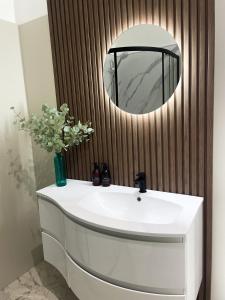 uma casa de banho com um lavatório branco e um espelho. em Kenavara House em Oban