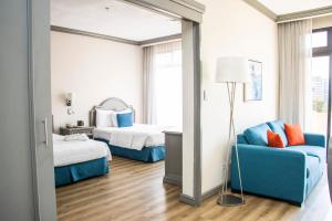 Habitación de hotel con 2 camas y sofá azul en Hotel Santander Plaza, en Guatemala