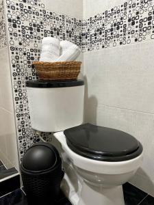 Baño con aseo con asiento negro y cesta en Apartamento pinares Santa Rosa en Santa Rosa de Cabal