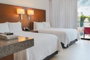 a hotel room with two beds and a balcony at Fiesta Inn Playa del Carmen in Playa del Carmen