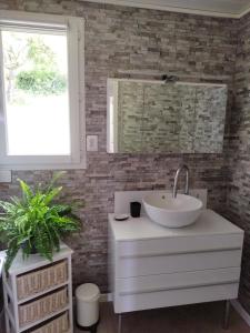 a bathroom with a white sink and a brick wall at Les Ecureuils 4 / 6 personnes in Seigy
