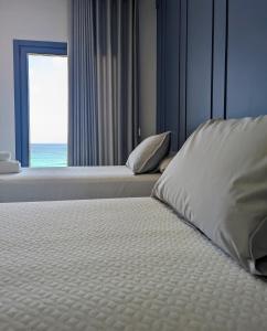 a bedroom with two beds and a window with the ocean at Restaurante Hostal Náutico de Razo in Carballo