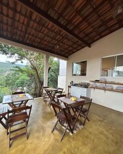 a dining room with tables and chairs and a kitchen at Pôr do Sol Suítes in Lençóis