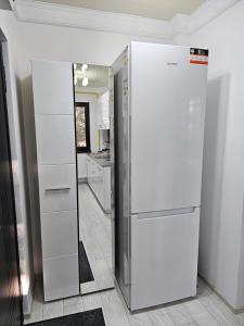 einen weißen Kühlschrank in einer Küche mit Spiegel in der Unterkunft APARTAMENT 12 RO&MARIO BARLAD in Bîrlad