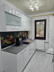 una cucina con armadi bianchi, lavandino e finestra di APARTAMENT 12 RO&MARIO BARLAD a Bîrlad