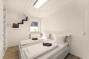 2 camas en una habitación blanca con escalera en Kanalufer-Oase in Eilsum, en Krummhörn