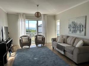 een woonkamer met een bank en 2 stoelen bij Bella Casa - Seaview-Beach Club Apartment in Kaapstad