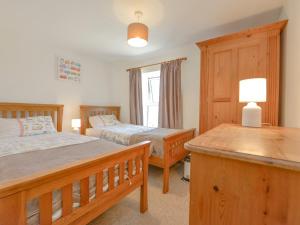 ウェイドブリッジにあるPrimrose Cottageのベッドルーム1室(ベッド2台、ランプ付きテーブル付)