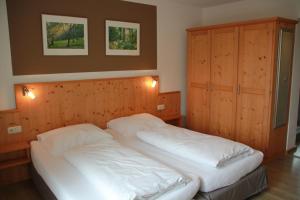 two beds in a bedroom with wooden walls at Pension Kellerer in Raubling +30 photos