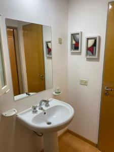 ein weißes Badezimmer mit einem Waschbecken und einem Spiegel in der Unterkunft Departamento Centrico 2 dormitorios in Neuquén