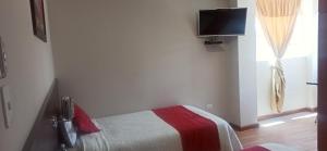a bedroom with a bed and a tv on the wall at Hotel Versailles in Ambato