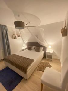 a white bedroom with a bed and a chair at Harzperle 3 II zentrales 3 Zi Apartment II Familien in Bad Harzburg
