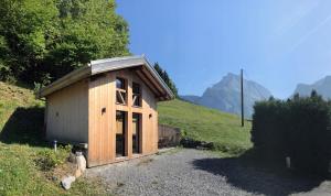 a small wooden building on a grassy hill at Chalet*** au pied d'une prairie face à la montagne in Sixt