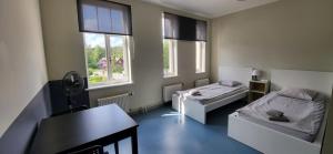 Pokój z 2 łóżkami, stołem i oknami w obiekcie Hostel Nr.2 w mieście Rauna