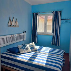 - une chambre bleue avec un lit et une fenêtre dans l'établissement Casa do Portão Azul - Espadarte, à Atouguia da Baleia