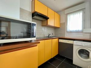 a kitchen with yellow cabinets and a washing machine at Lumineux 2 pièces Paris nord-est in Pantin