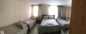 Habitación pequeña con 2 camas y ventana en Pousada Dubai en Itabuna