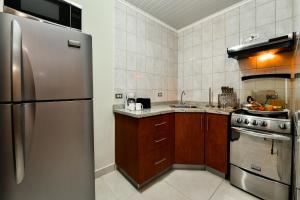 a kitchen with a stainless steel refrigerator and wooden cabinets at NEW Apartment Ocean View with Amazing Sunsets in Sabana Berde