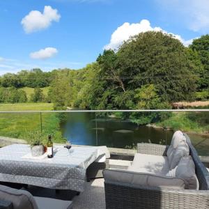 a patio with a table and chairs next to a lake at Riverside Retreat in Llandysul