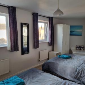a bedroom with two beds and two windows at Sea Escape The Tardiis 2 mins from Aberavon Beach Driveway parking in Port Talbot