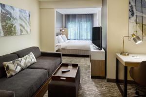 um quarto de hotel com um sofá e uma cama em SpringHill Suites Charlotte University Research Park em Charlotte