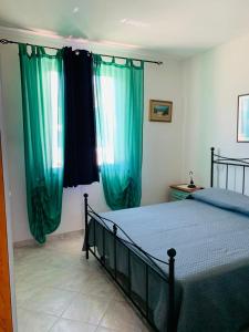 Schlafzimmer mit einem Bett und grünen Vorhängen in der Unterkunft Valledoria Residenza sole e mare in Codaruina