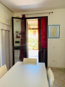 einen weißen Tisch und Stühle in einem Zimmer mit Fenster in der Unterkunft Valledoria Residenza sole e mare in Codaruina