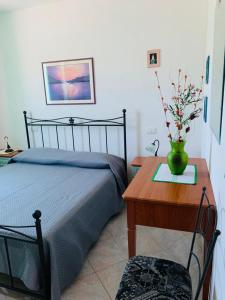 ein Schlafzimmer mit einem Bett und einem Tisch mit einer Vase darauf in der Unterkunft Valledoria Residenza sole e mare in Codaruina