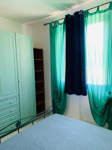 Schlafzimmer mit blauen Vorhängen, einem Bett und einem Fenster in der Unterkunft Valledoria Residenza sole e mare in Codaruina