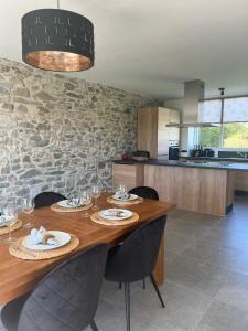 een eetkamer met een houten tafel en een stenen muur bij Le Refuge de Toine Gîte rural 3 épis in Chimay