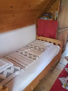 a wooden bed in a room with a red chair at Apartmani Planinska kuća, Jagodnja in Krupanj