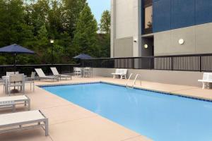 a swimming pool with chairs and umbrellas next to a building at Hampton Inn Beckley in Beckley